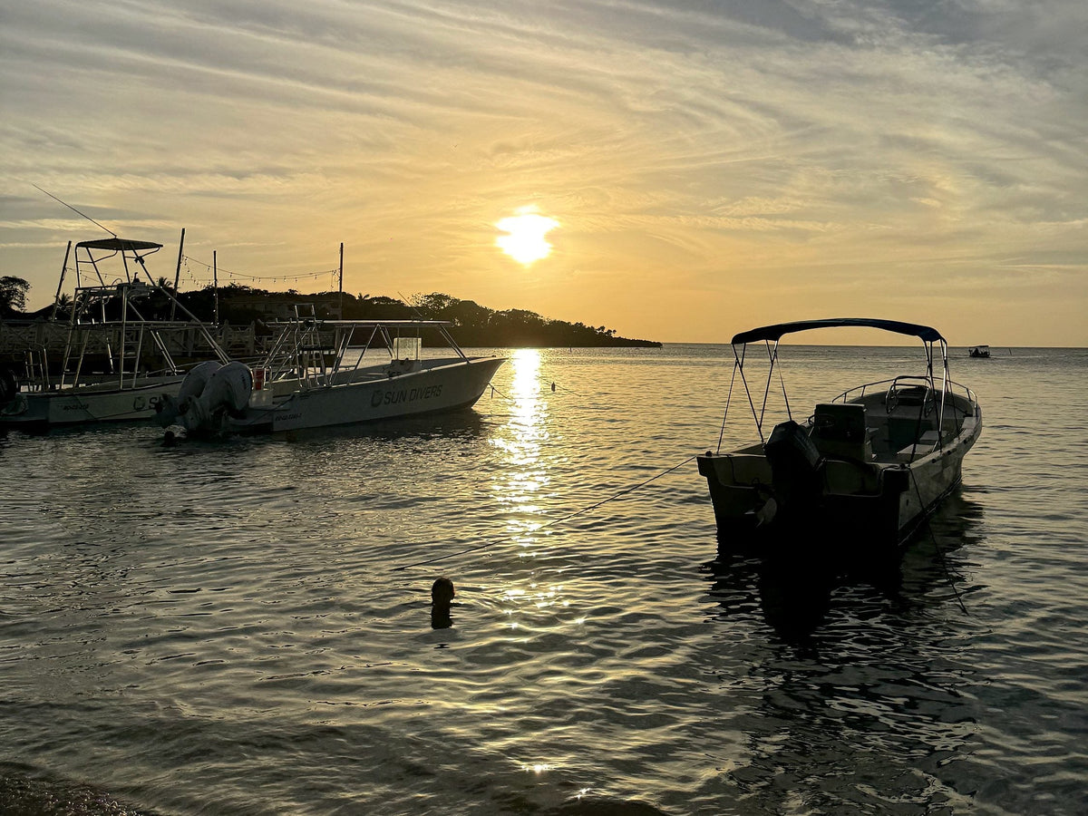 Boats at anchor off West End, Roatan, under a warm sunset sky